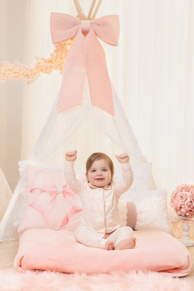 one year old girl smiling on a pink bow tent in a chicago studio