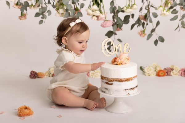 one year old girl tasting cake during a floral cake smash studio session