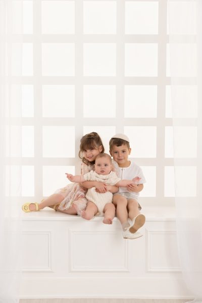 three siblings posed in a Chicago studio on a white window