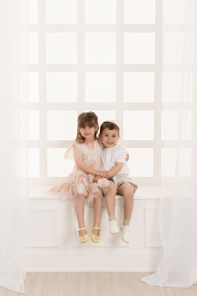 siblings posing one a white window in a chicago studio