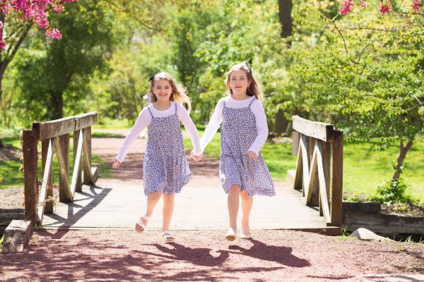 two sisters running over a bridge