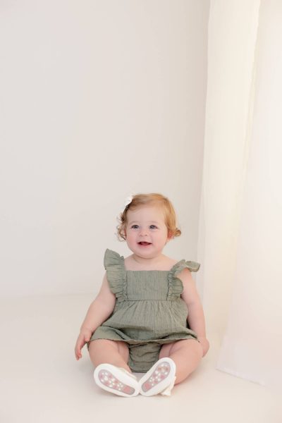 one year old girl smiling in the lifestyle area of a studio