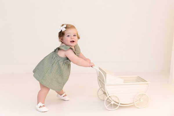 one year old girl pushing a stroller at a Chicago studio portrait session