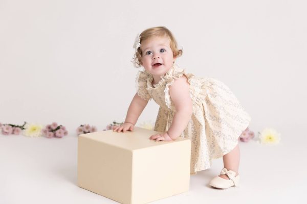 one year old girl smiling at her floral cake smash