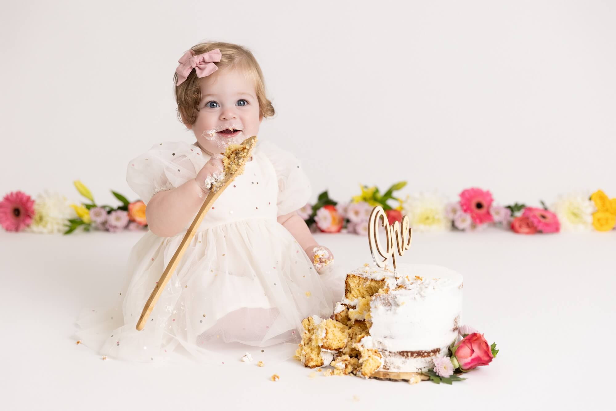 one year old girl smashing cake at her floral cake smash