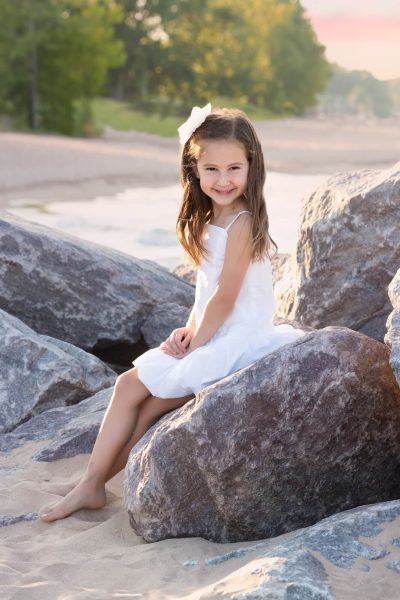 girl smiling on the rocks at a sunset beach session in Chicago