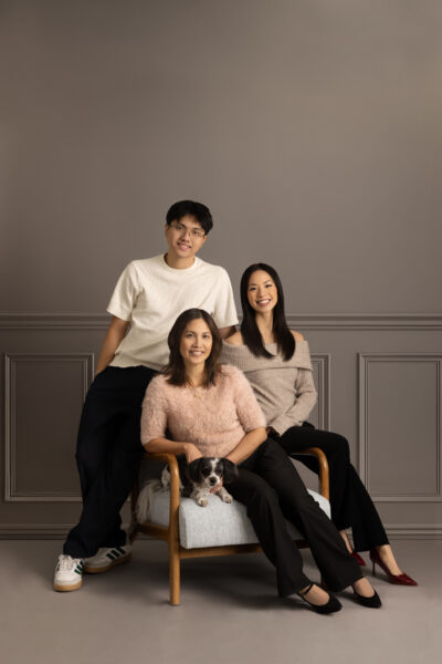 mother and teenage children posed against a gray backdrop