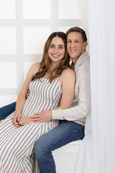 portrait of a couple sitting on a white window in the Chicago studio