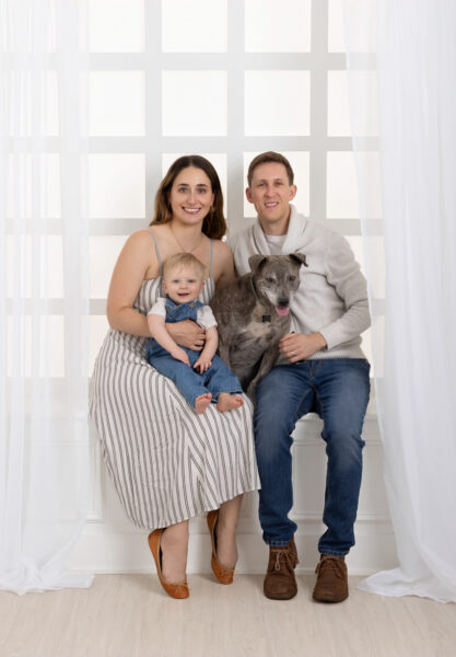 Portrait of a family with their one year old boy and dog in the window area of a Chicago studio