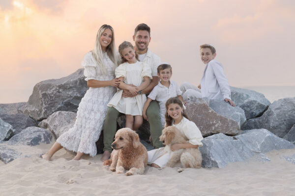 Family posing with their dogs on the rocks at a beach