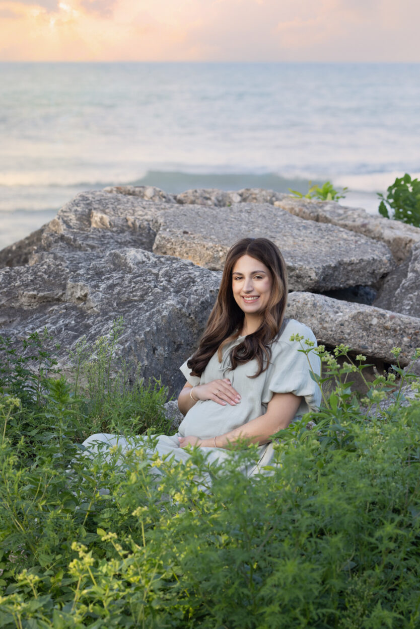 Mom posed at a Lake Michigan Maternity session in Dawes Park on the rocks at sunset