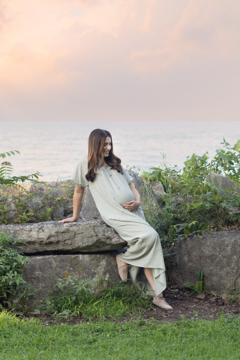 Candid image of a Mom during a maternity session in Chicago at Lake Michigan posed on rocks holding her belly