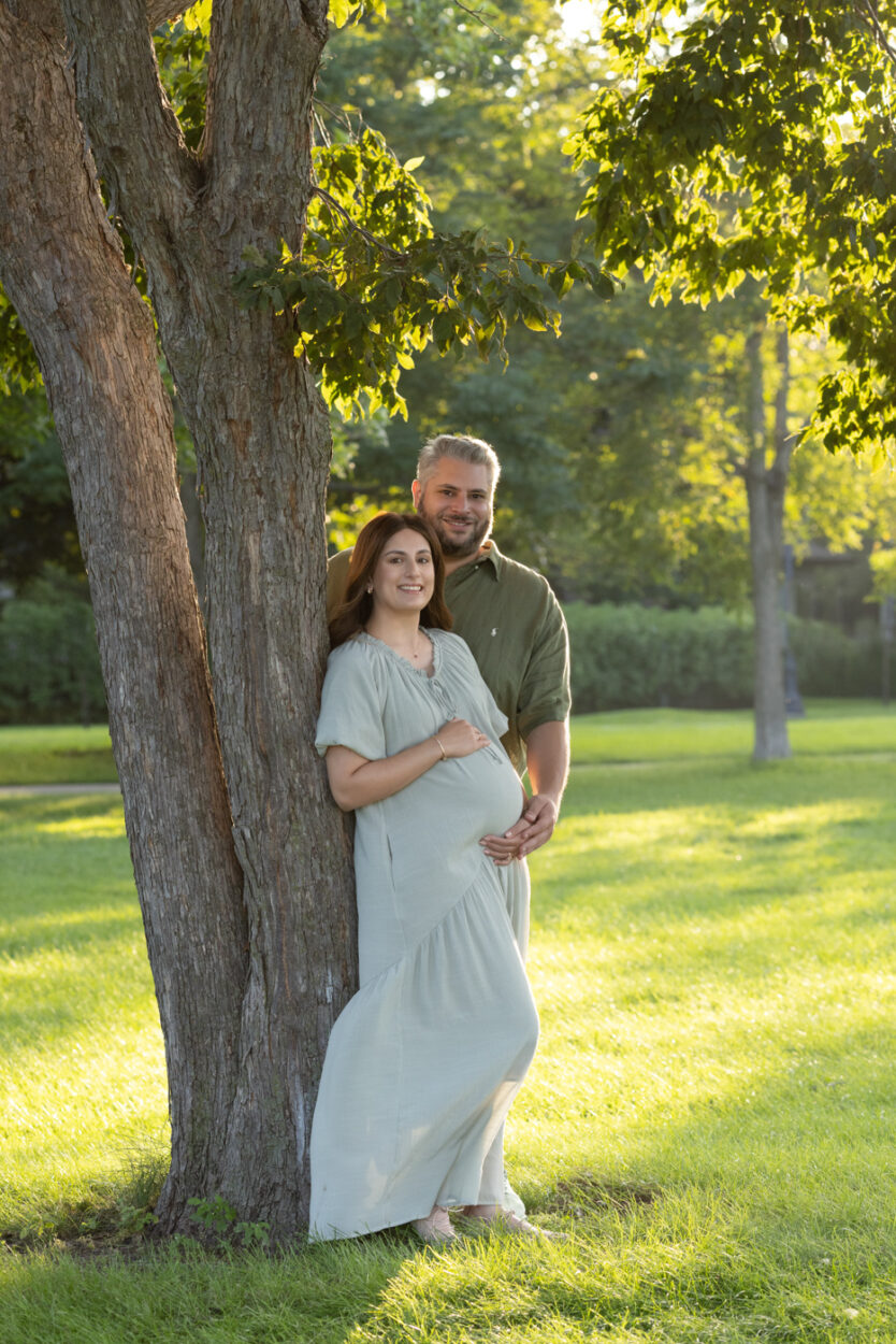 Couple posed in chicago during a maternity session in a park against a tree