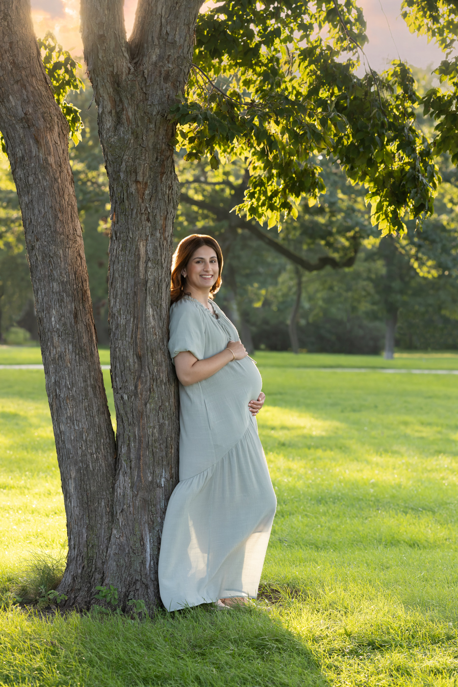 Chicago Mom posed against a tree holding her stomach during a maternity session