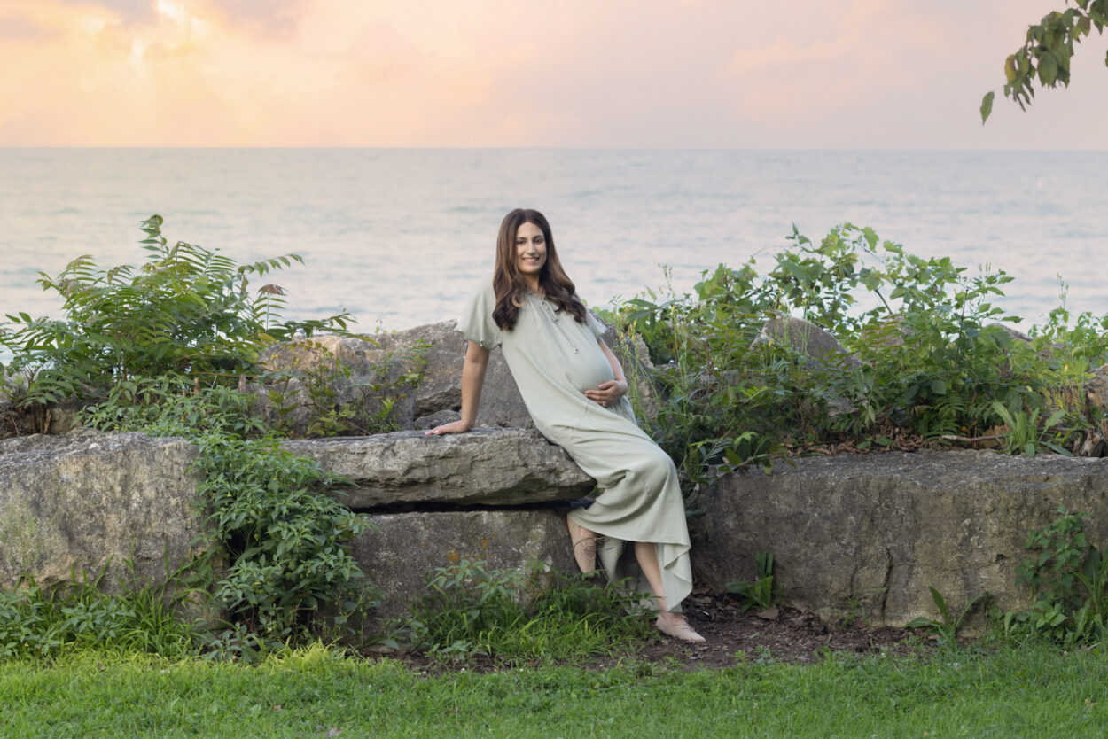 Mom sitting on the rocks at Dawes Park maternity session in Lake Michigan